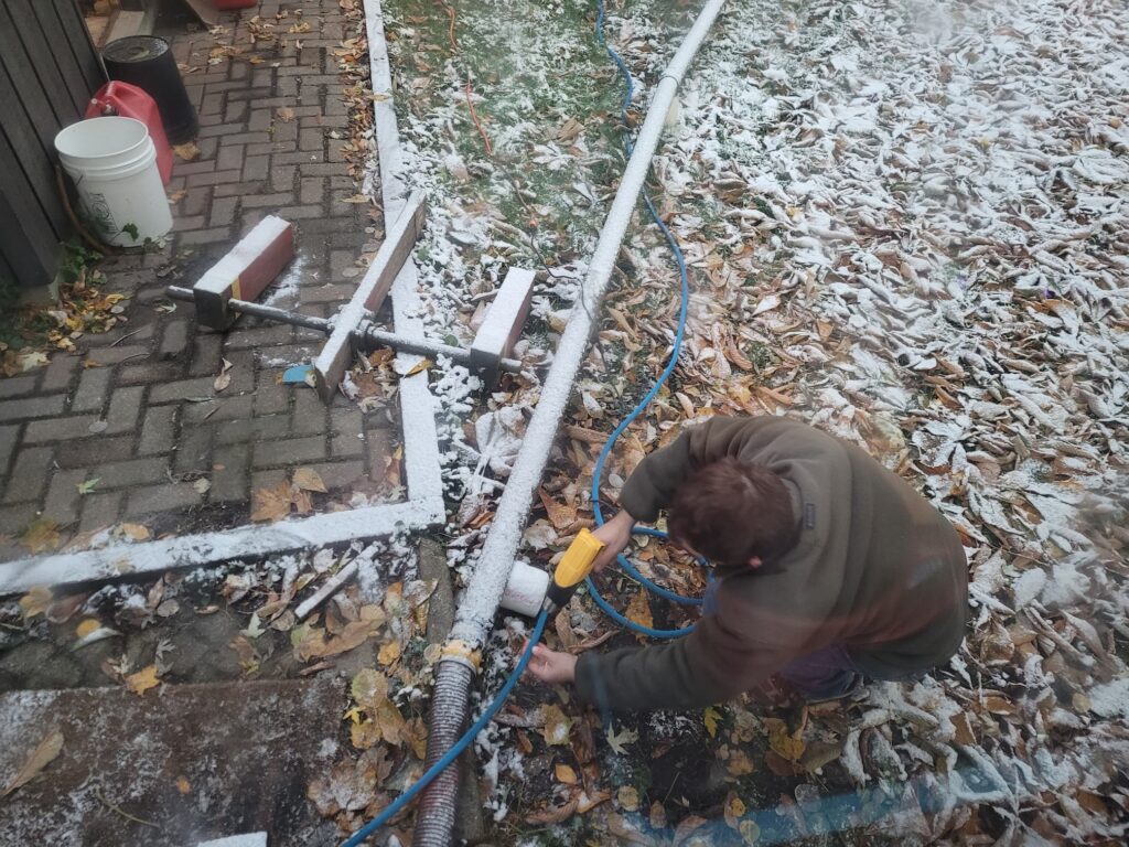 Photo of Josh thawing out a frozen hose with a heat gun