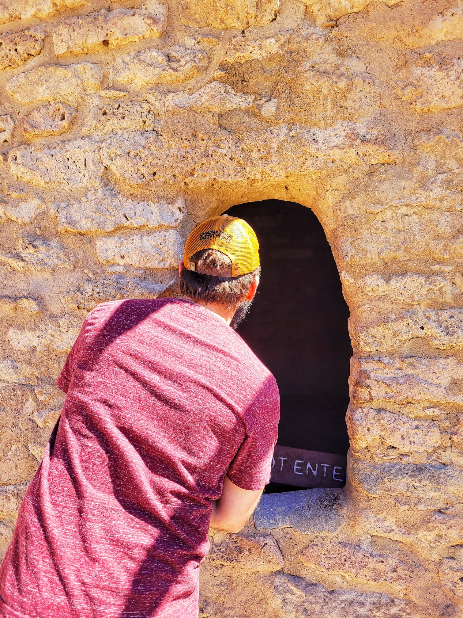 photo of josh looking into a cavate at bandelier national monument